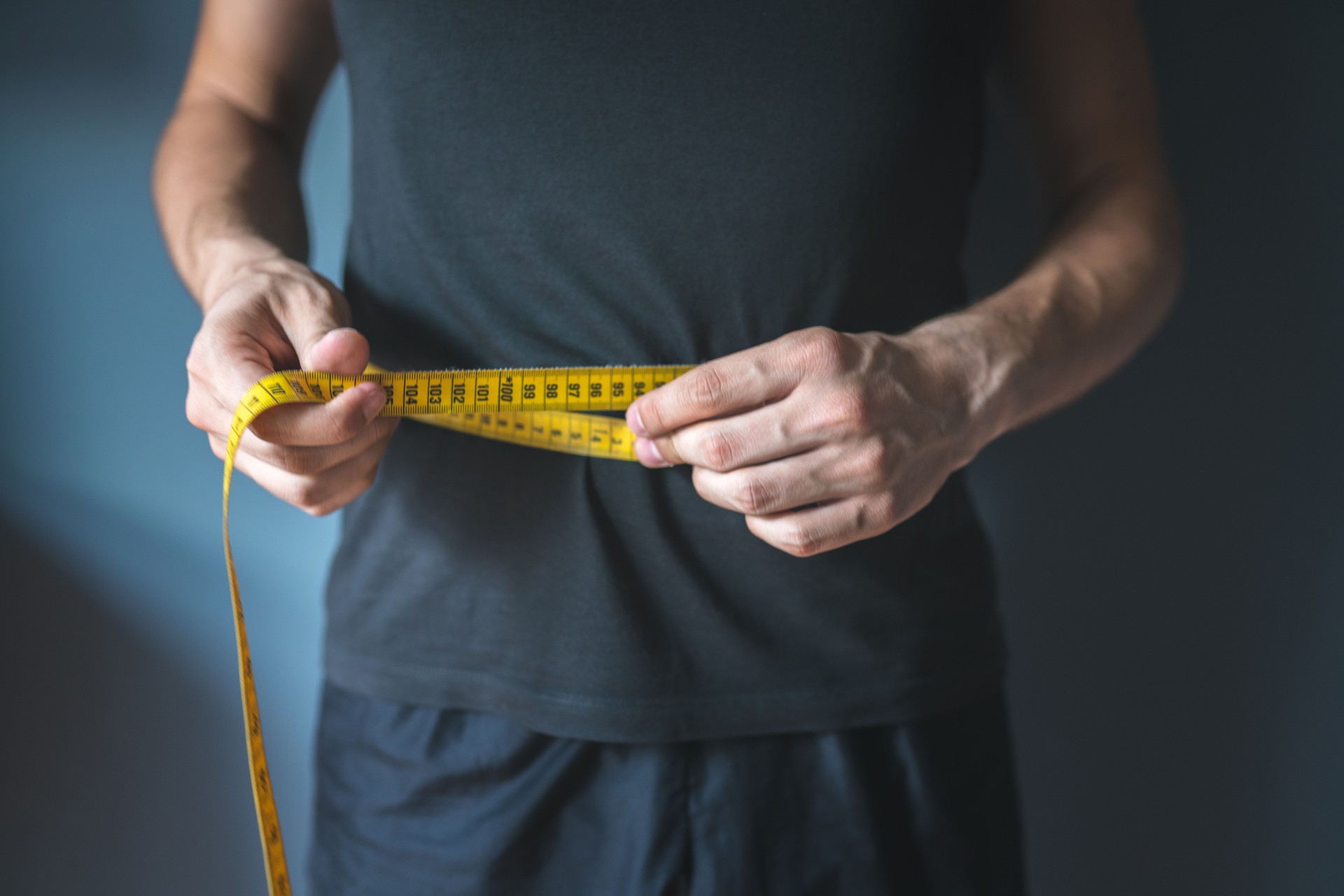 Uomo magro che misura la vita. Stile di vita sano, dimagrimento del corpo, concetto di perdita di peso.